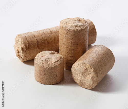 Brown compressed biomass briquettes scatted against white background