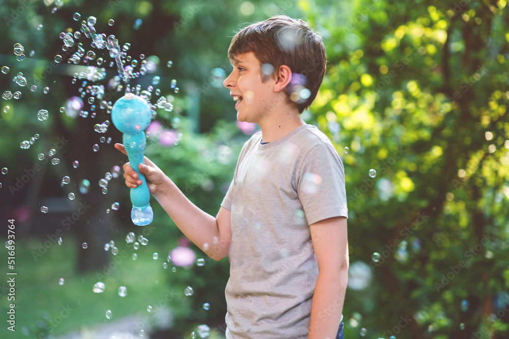 Happy kid boy having fun with blowing soap bubble blower. Preteen child playing on sunny summer day. Happy active funny healthy kid. Activity for children. Happy kid boy having fun with blowing soap bubble blower. Preteen child playing on sunny summer day. Happy active funny healthy kid. Activity for children.