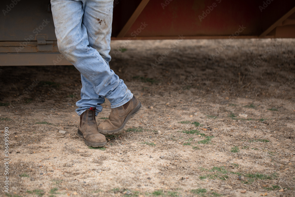 crossed legs of man standing wearing dirty jeans and work boots crossed legs of man standing wearing dirty jeans and work boots