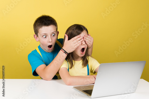 Boy and protective boy watching inappropriate content on internet isolated on yellow background. Parental control concept.