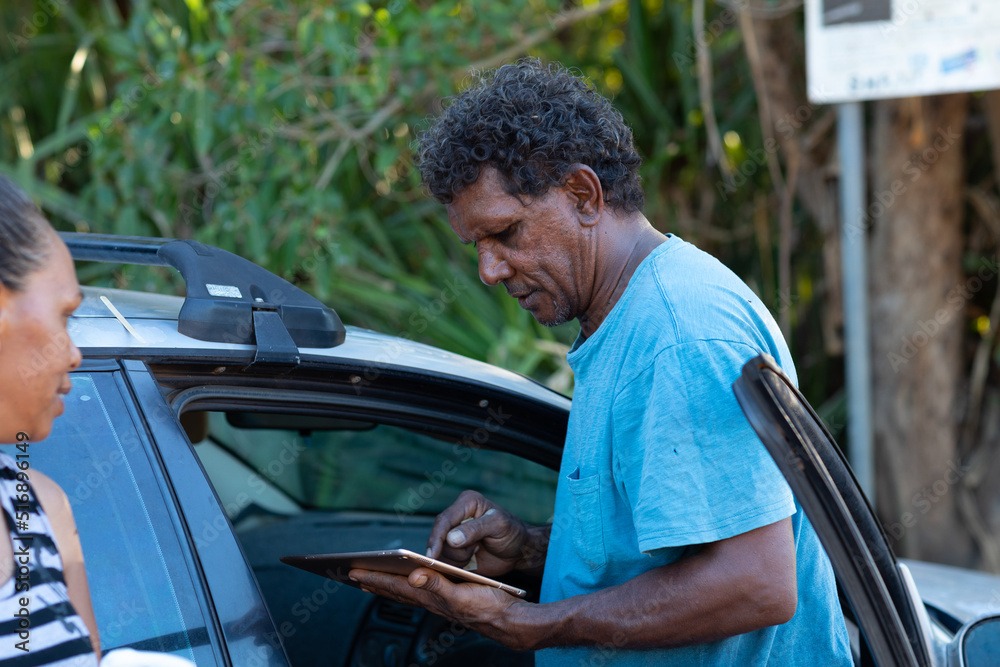 man and woman next to car with man looking at digital tablet man and woman next to car with man looking at digital tablet