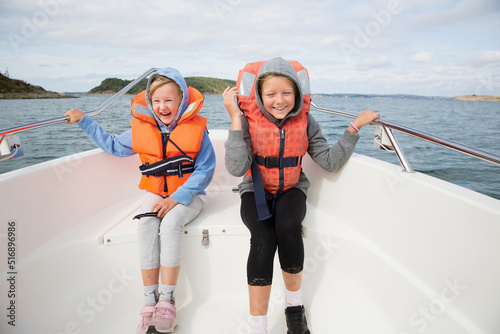 Smiling girls in life jackets sitting on boat photo