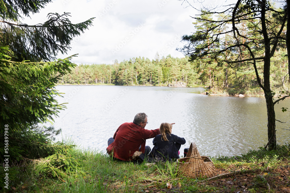 Father and daughter sitting by lake Father and daughter sitting by lake