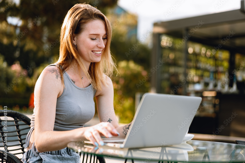 Happy beautiful young woman working on laptop in street cafe Happy beautiful young woman working on laptop in street cafe