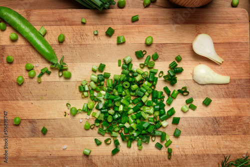 Fototapeta Naklejka Na Ścianę i Meble -  vegetables on a wooden kitchen board, sliced green onions, peas on a wood background, concept of fresh and healthy food, still life