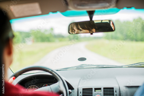 Woman seen in reer view window driving car photo