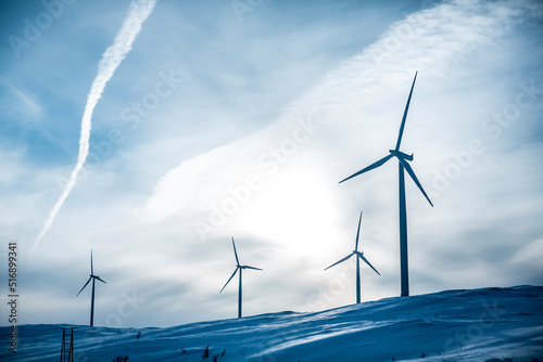 Low angle view of wind turbines on snowy hill