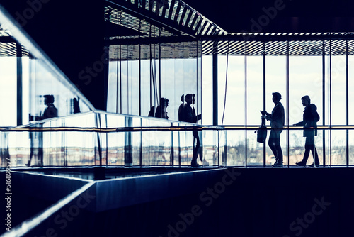 Silhouette of people walking by window of building