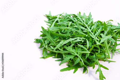 A bunch of arugula on white in the midday light. Heap of green fresh rucola or arugula leaf