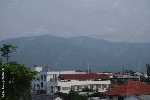 Top view of buildings in Chiang Mai city with a background of a mountain and blue cloudy sky in Chiang Mai, Thailand © Mart