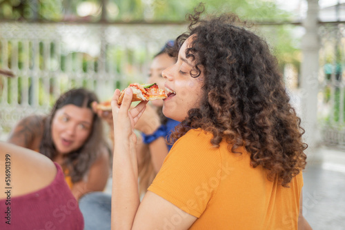 Young woman sitting eating mexican pizza with friends.