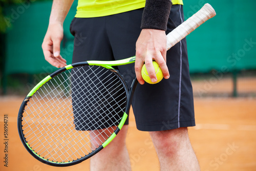 Closeup male tennis player holding racket and ball.