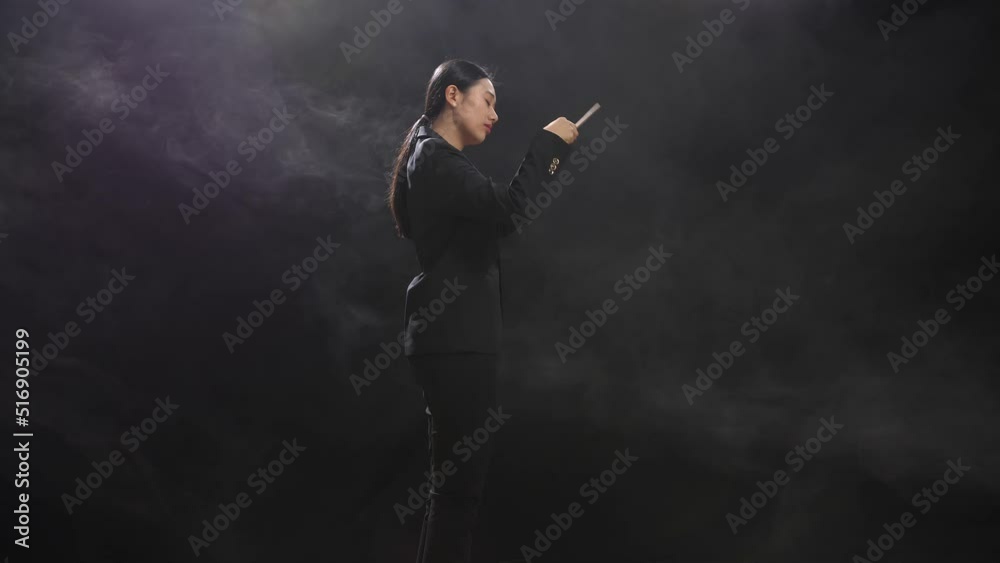 Side View Of Asian Conductor Woman Holding A Baton Closing Her Eyes And Showing Gesture In The Black Studio With Fog
Side View Of Asian Conductor Woman Holding A Baton Closing Her Eyes And Showing Gesture In The Black Studio With Fog