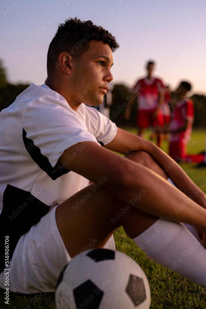 Side view of thoughtful sad caucasian male player looking away and sitting against clear sky