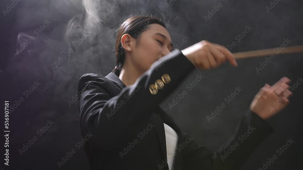 Side View Of Asian Conductor Woman Holding A Baton And Showing Gesture Quickly In The Black Studio With Fog
Side View Of Asian Conductor Woman Holding A Baton And Showing Gesture Quickly In The Black Studio With Fog