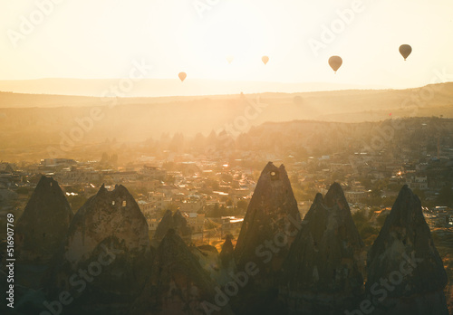 Golden sunrise over Goreme town in Cappaocia front side sunlight directional with balloons on air in sunny hazy autumn calm morning