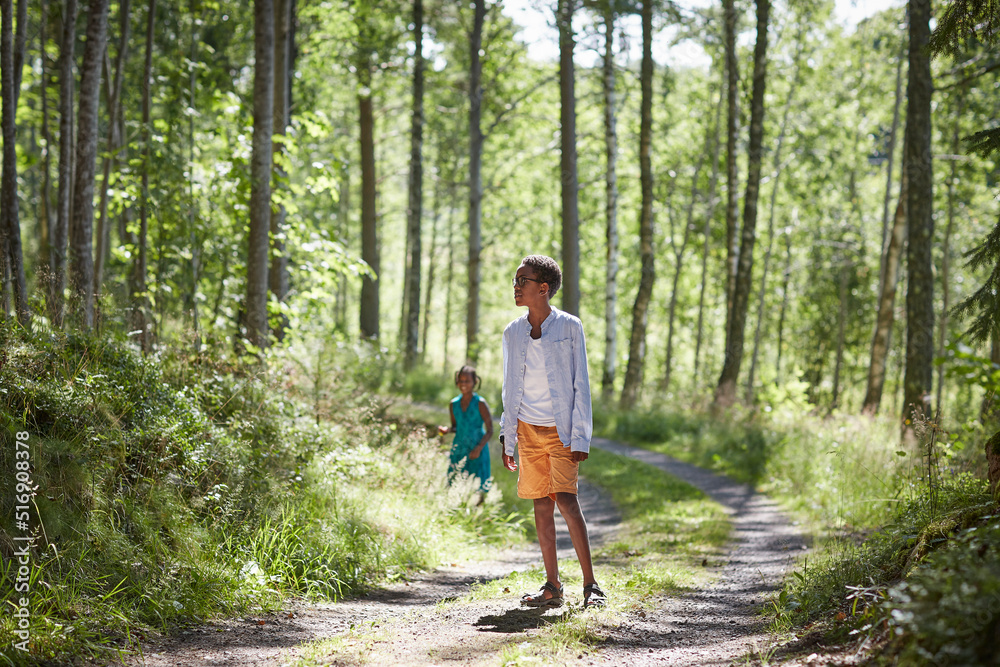 Siblings walking on path in forest Siblings walking on path in forest