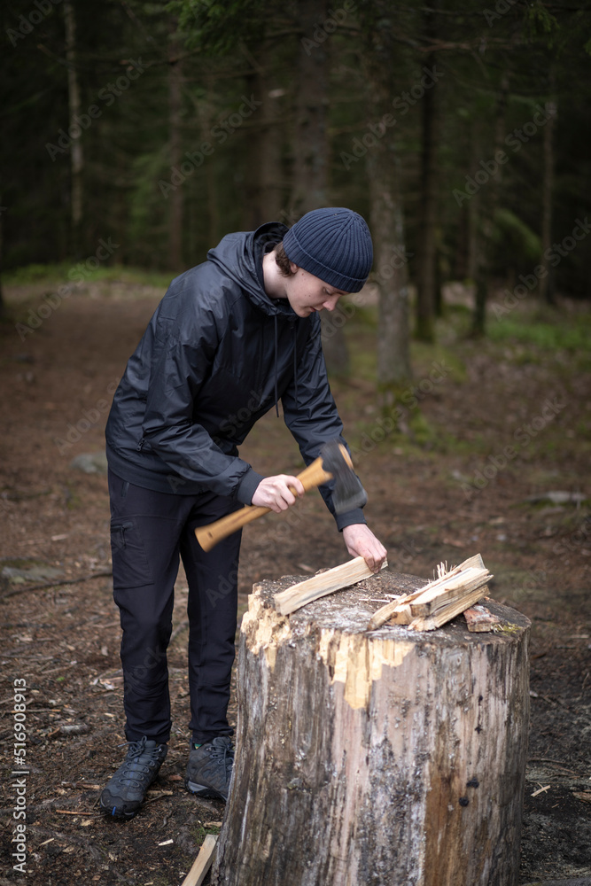 Teenage boy chopping firewood on tree stump Teenage boy chopping firewood on tree stump