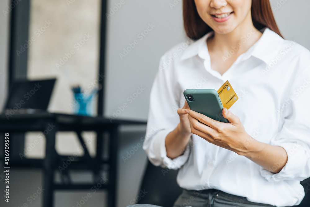 Beautiful woman holding a credit card, she uses a credit card to pay for goods and services online, the concept of using a credit card for online shopping, ordering goods and services on the website. Beautiful woman holding a credit card, she uses a credit card to pay for goods and services online, the concept of using a credit card for online shopping, ordering goods and services on the website.