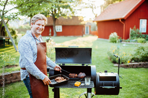 Young man cooking meat on barbecue photo