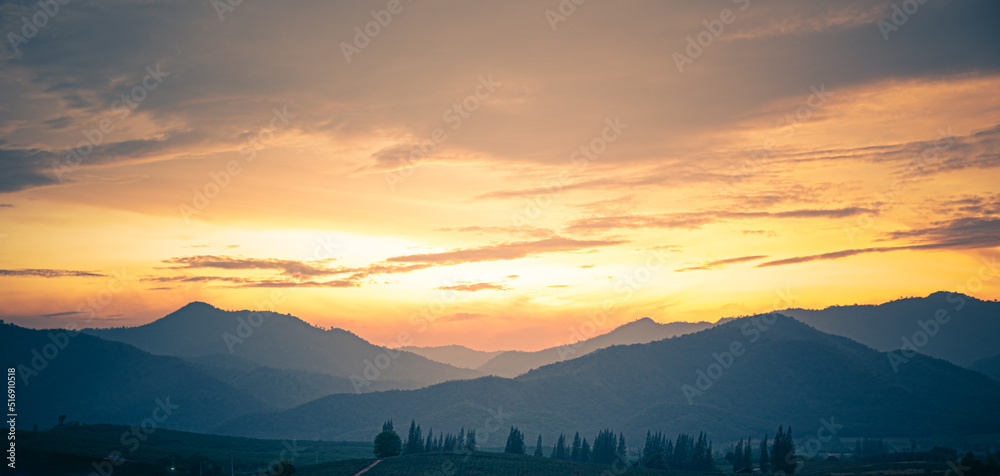 Orange and yellow sunset with mountains silhouettes. Gradient vivid nature background.