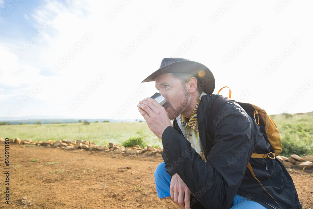 Man drinking from cup while hiking