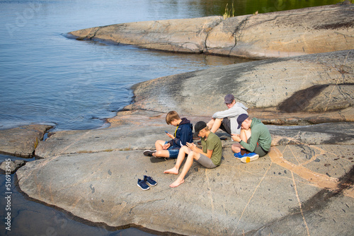 Teenage boys sitting on rock by sea photo