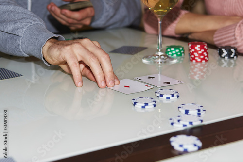 Laying out cards on the table in poker game. Players with dices and cards. Glass of champagne. Gambling concept. Candid moment. Poker background photography. Selective focus