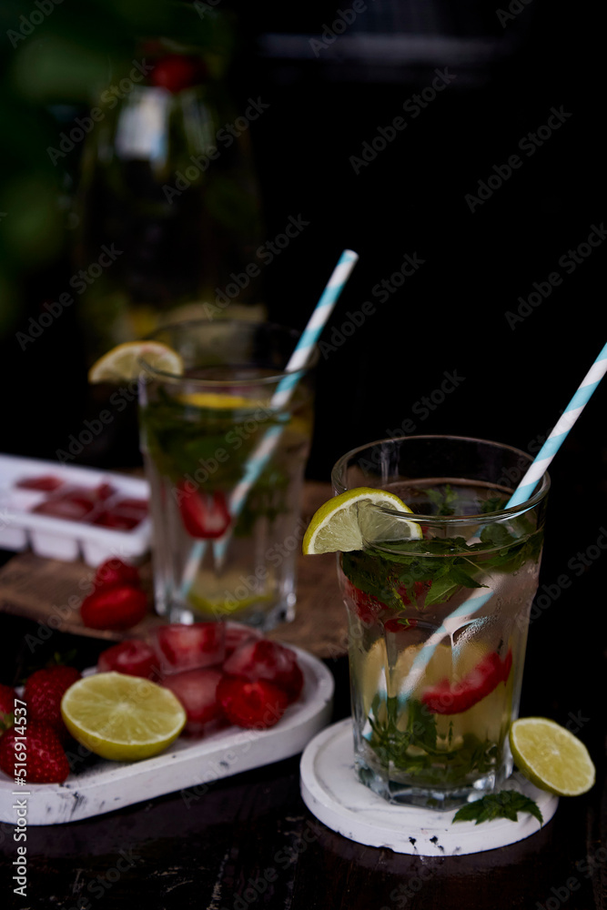 Fototapeta premium Summer infused water with lemon, lime, mint and strawberries. Refreshing, diet, detox natural fortified water. Hard seltzer with nootropics. Healthy natural cocktails. Summertime beverages