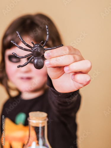 happy elementary girl shows a spider disguised as a skeleton wearing a T-shirt with a pumpkin design