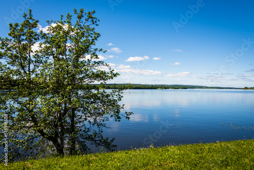 Fototapeta Naklejka Na Ścianę i Meble -  Landscape overlooking the lake on a clear sunny day. Lake Onega with the embankment of the Kizhi Island, Karelia, Russia. The concept of tourism in Russia.
