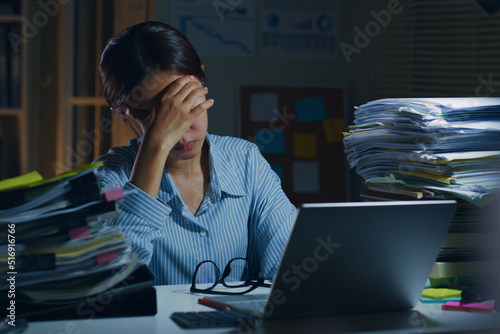 Young Asian office employee feeling tired, fatigue, exhausted while working overtime at night in office