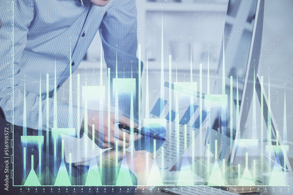 Double exposure of chart with businessman typing on computer in office on background. Concept of hard work.