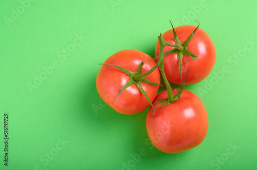 top view of tomatoes on a branch on a green background with copy space