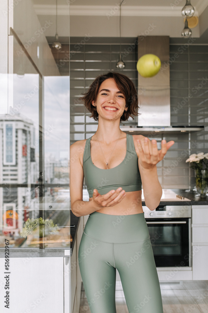 Cute young woman luffing at camera in home . Image of brunette carre caucasian girl staying in the kitchen wear green top and leggings. Lifestyle, home concept Cute young woman luffing at camera in home . Image of brunette carre caucasian girl staying in the kitchen wear green top and leggings. Lifestyle, home concept