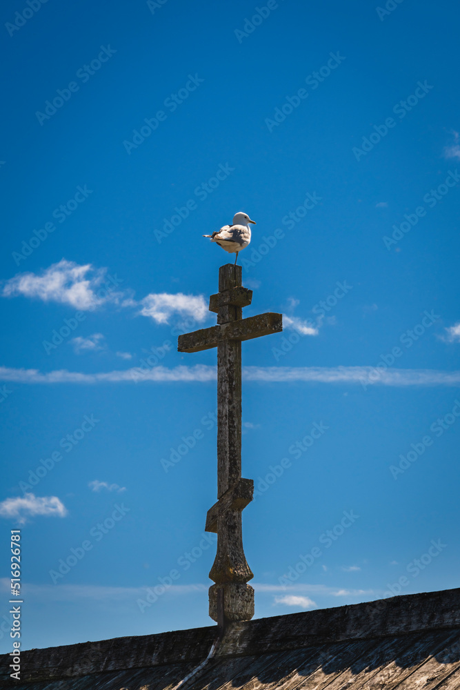 Wooden Orthodox cross on the roof of the building against the blue sky. Kizhi Island, Karelia, Russia.