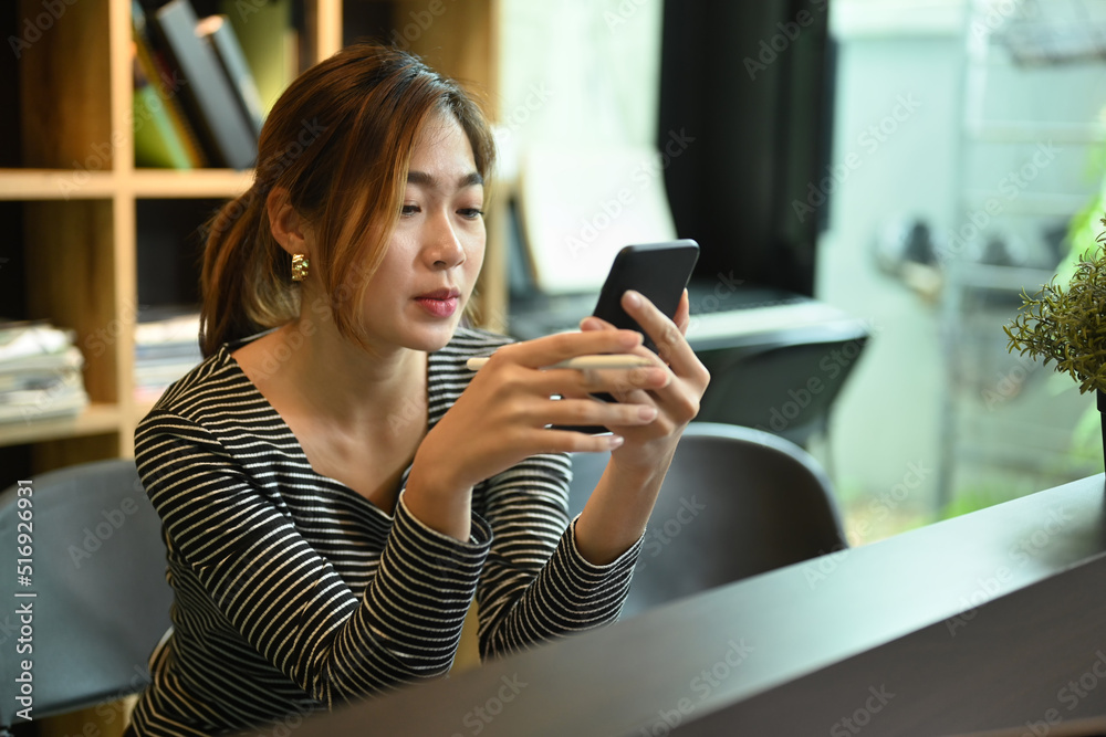 Young asian woman using mobile phone, sitting at co working space in modern office