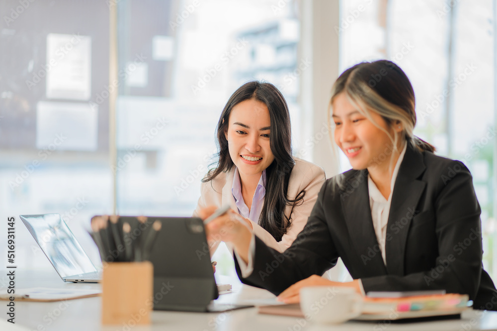 Two Asian female accountants working in the office with laptop computers and financial documents on the table. Two Asian female accountants working in the office with laptop computers and financial documents on the table.