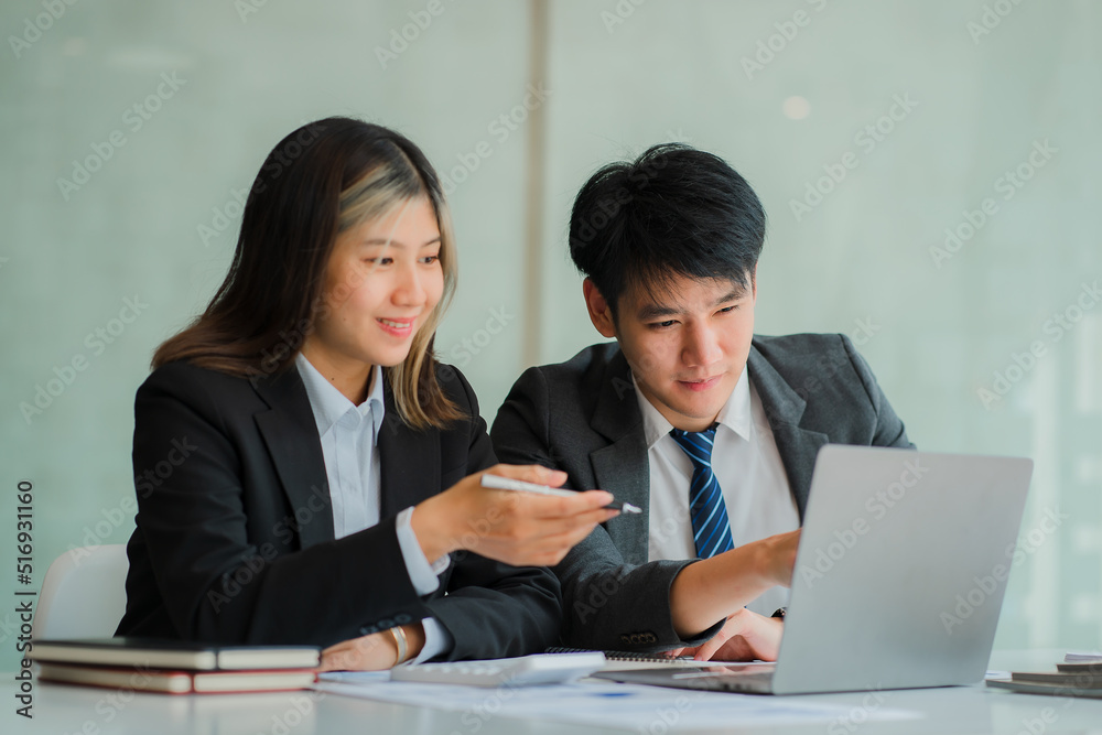Young businessman chatting with colleagues and sharing laptops and smiling happily and confidently. With data analysis in financial documents, concepts work together with a smile on their face. Young businessman chatting with colleagues and sharing laptops and smiling happily and confidently. With data analysis in financial documents, concepts work together with a smile on their face.