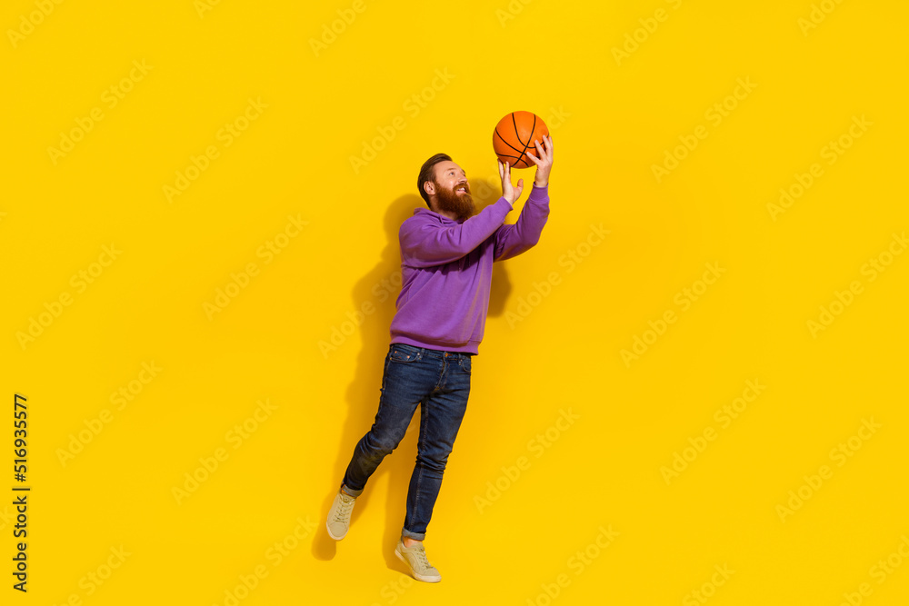 Full length photo of excited cool man wear violet sweatshirt throwing basketball ball isolated yellow color background