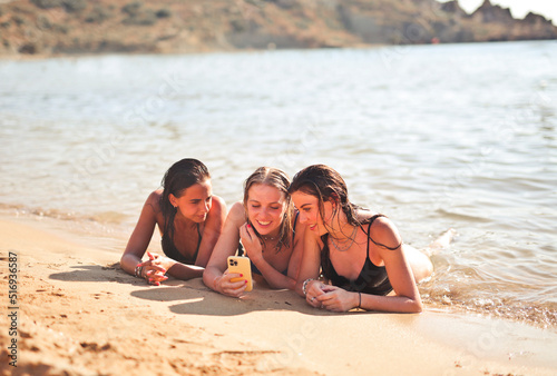 three girls lying on the beach with a smartphone