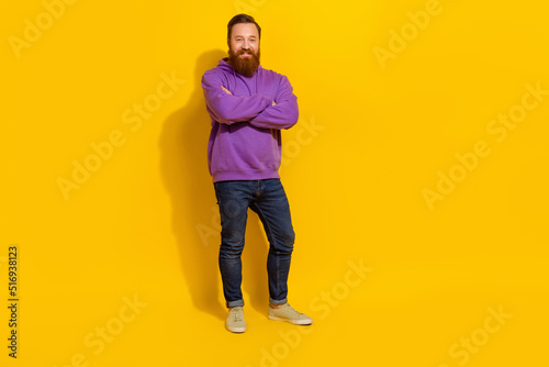 Full length photo of cool confident man wear violet sweatshirt arms crossed empty space isolated yellow color background