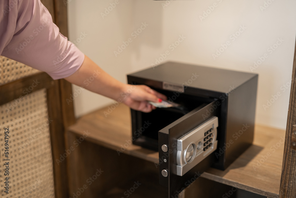 Steel safe with money. Hand putting password in the safety money box in hotel room Steel safe with money. Hand putting password in the safety money box in hotel room