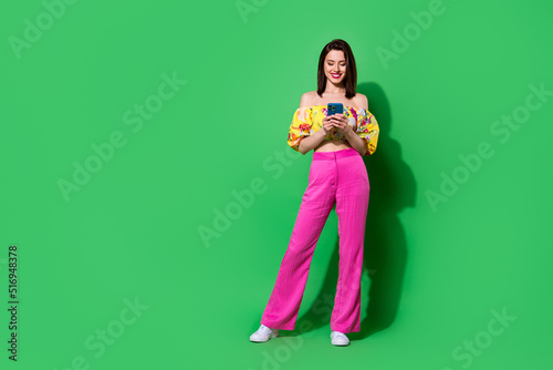 Full length photo of adorable sexy girl dressed off shoulders top writing modern device isolated green color background