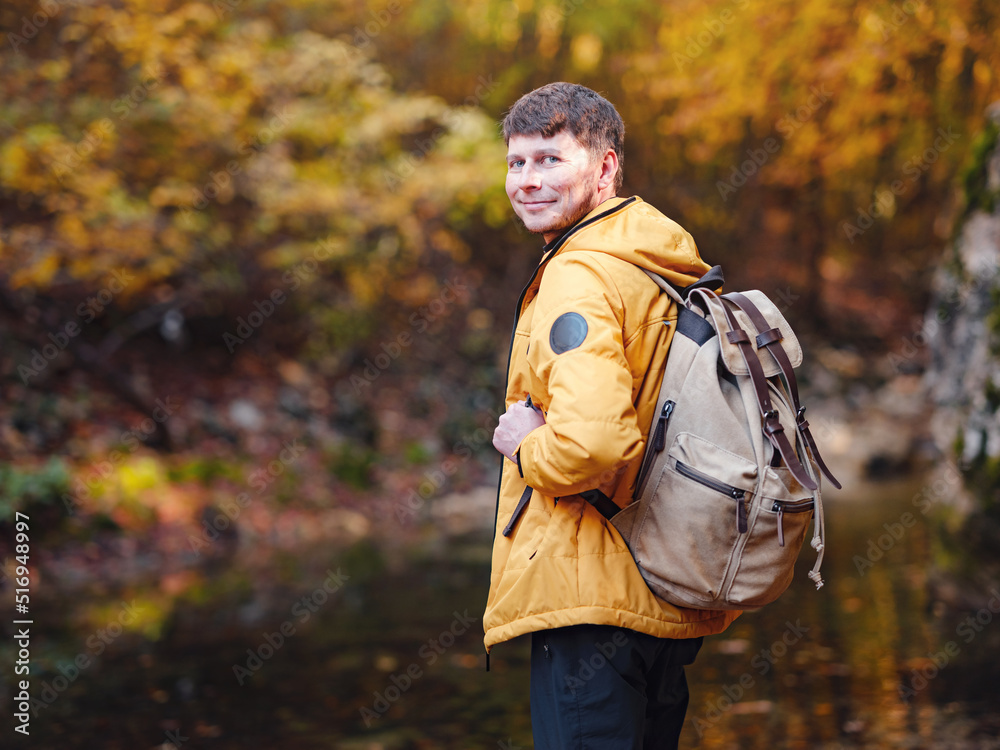 Travel and road trip concept at autumn. Adventure and active lifestyle in nature. Tourist hiking in forest. Caucasian man in yellow jacket walks in woods. Travel and road trip concept at autumn. Adventure and active lifestyle in nature. Tourist hiking in forest. Caucasian man in yellow jacket walks in woods.