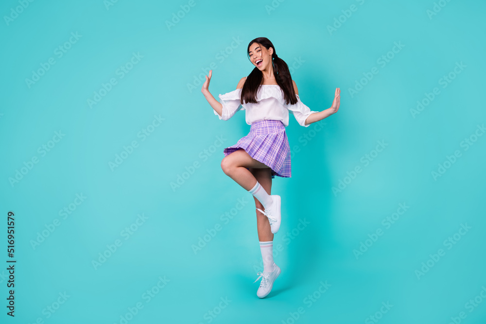 Full size photo of energetic cheerful girl jumping have fun good mood isolated on turquoise color background Full size photo of energetic cheerful girl jumping have fun good mood isolated on turquoise color background