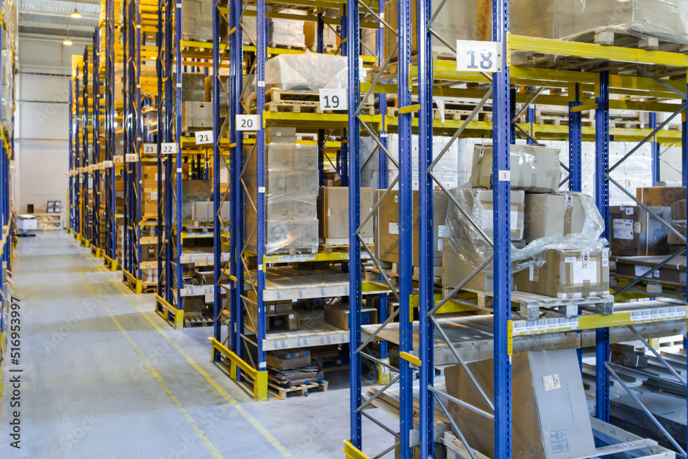 Interior of a modern warehouse storage with rows and goods boxes on high shelves Interior of a modern warehouse storage with rows and goods boxes on high shelves