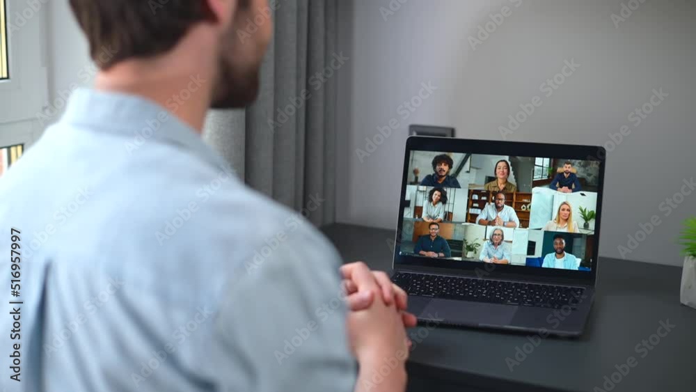 Virtual conference, online meeting. Young man using computer app for communicating with many people at same time together. Back view. Video call with diverse employees Virtual conference, online meeting. Young man using computer app for communicating with many people at same time together. Back view. Video call with diverse employees
