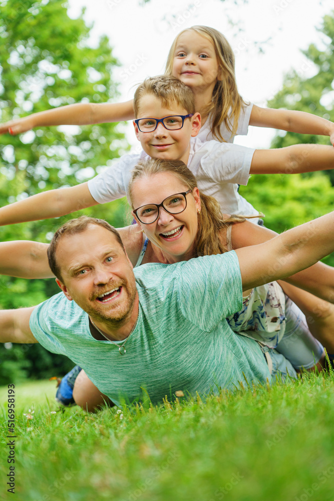 Fototapeta premium happy family lying on the green grass in the Park. The interaction of the children