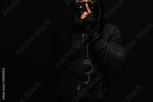 Cropped view of african american hooligan in handcuff showing secret gesture isolated on black